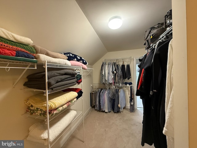 walk in closet with light carpet and vaulted ceiling