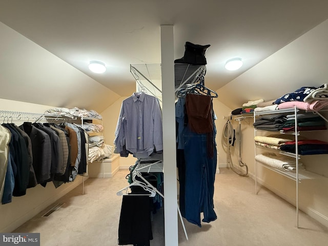 spacious closet featuring light colored carpet and lofted ceiling