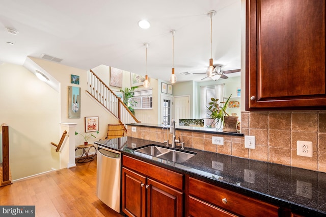 kitchen featuring ceiling fan, sink, stainless steel dishwasher, dark stone counters, and light hardwood / wood-style floors