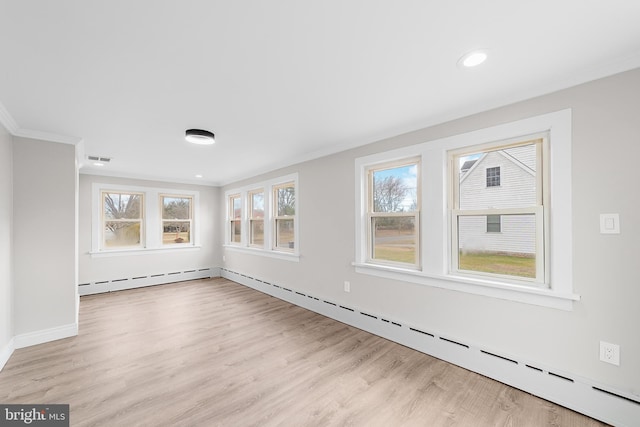 empty room with light wood-type flooring, a baseboard radiator, and plenty of natural light