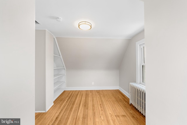 bonus room with vaulted ceiling, light hardwood / wood-style flooring, and radiator