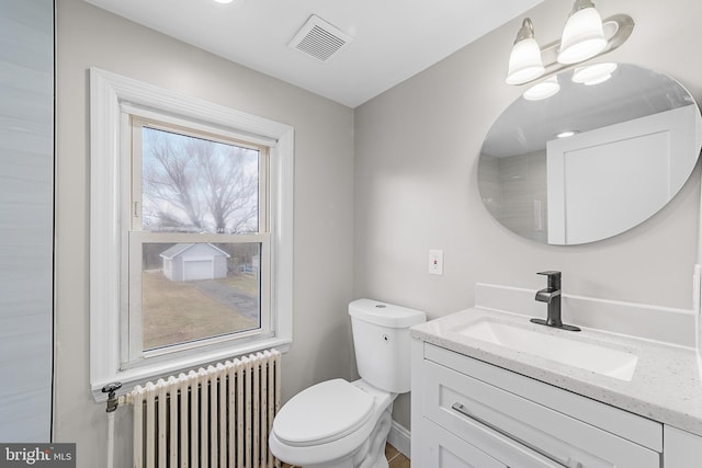 bathroom featuring radiator heating unit, vanity, toilet, and plenty of natural light