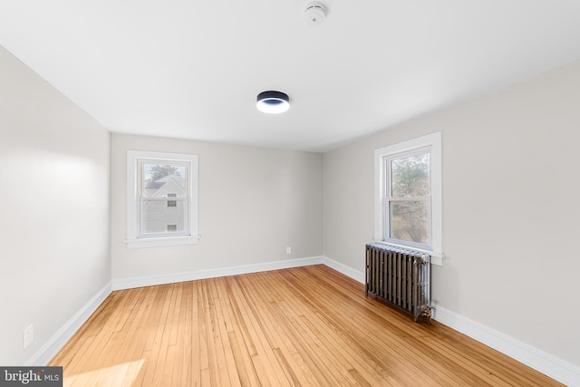 unfurnished room with radiator, a healthy amount of sunlight, and light wood-type flooring