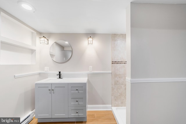 bathroom featuring hardwood / wood-style floors, vanity, baseboard heating, and walk in shower