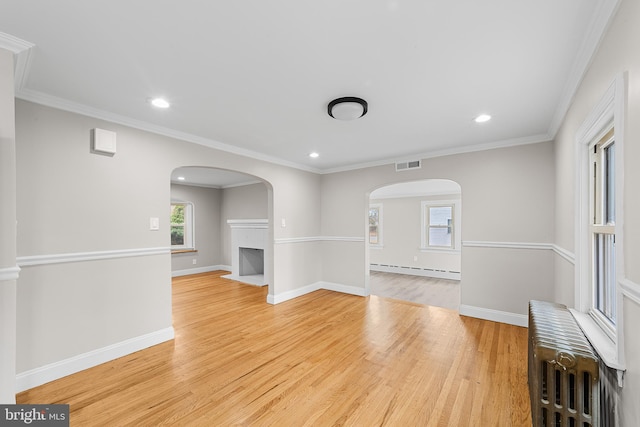 unfurnished living room featuring radiator heating unit, crown molding, light wood-type flooring, and baseboard heating