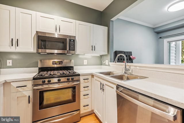 kitchen featuring white cabinets, sink, ornamental molding, kitchen peninsula, and stainless steel appliances