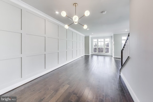 unfurnished living room with crown molding, dark hardwood / wood-style floors, and an inviting chandelier