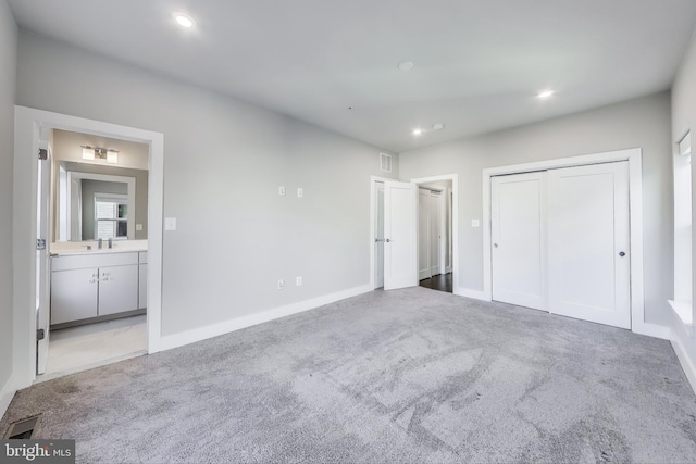 unfurnished bedroom featuring sink, light carpet, connected bathroom, and a closet