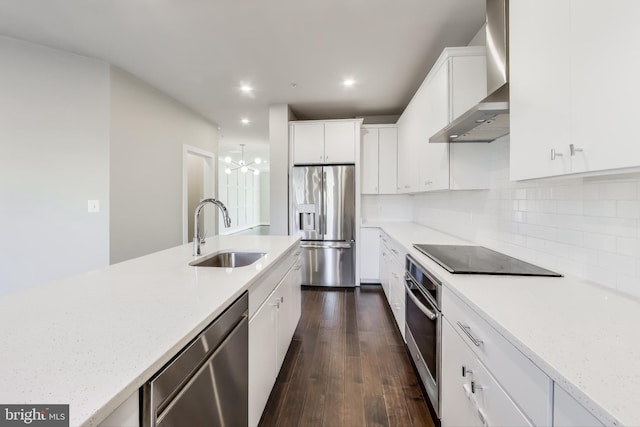 kitchen with white cabinets, wall chimney range hood, sink, appliances with stainless steel finishes, and tasteful backsplash