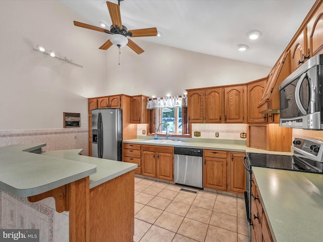 kitchen with ceiling fan, sink, a breakfast bar, light tile patterned flooring, and appliances with stainless steel finishes