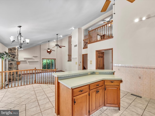 kitchen with high vaulted ceiling, ceiling fan with notable chandelier, tile walls, decorative light fixtures, and light tile patterned flooring