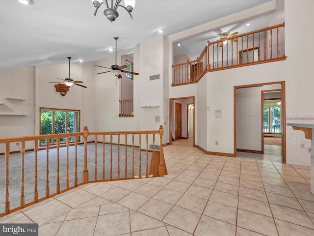 interior space with ceiling fan, light tile patterned flooring, and a high ceiling