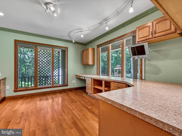 kitchen with a wealth of natural light, crown molding, built in desk, and light hardwood / wood-style floors