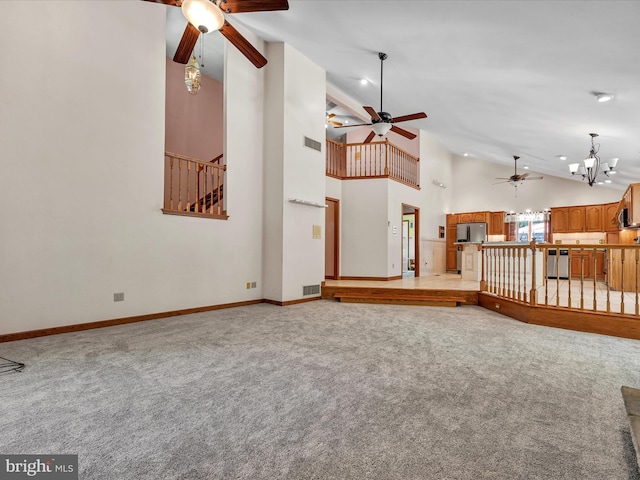 unfurnished living room with light carpet, high vaulted ceiling, and an inviting chandelier