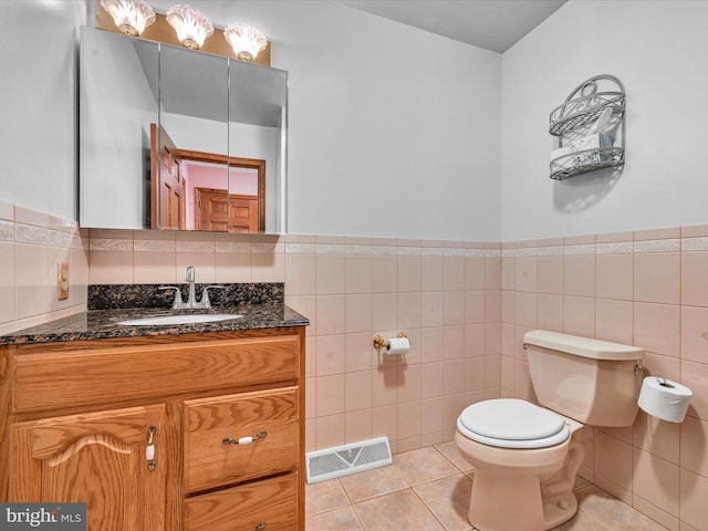 bathroom featuring tile patterned flooring, vanity, tile walls, and toilet