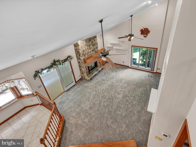 unfurnished living room with ceiling fan, a fireplace, high vaulted ceiling, and light colored carpet