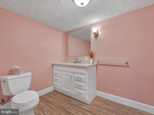 bathroom featuring hardwood / wood-style flooring, vanity, toilet, and a textured ceiling