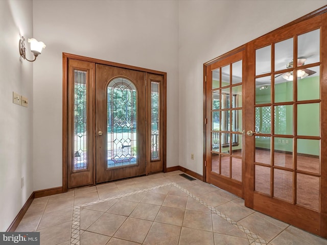 entryway featuring ceiling fan, light tile patterned floors, a high ceiling, and french doors