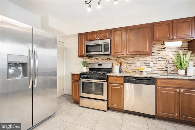 kitchen with light tile patterned flooring, light stone counters, stainless steel appliances, and tasteful backsplash