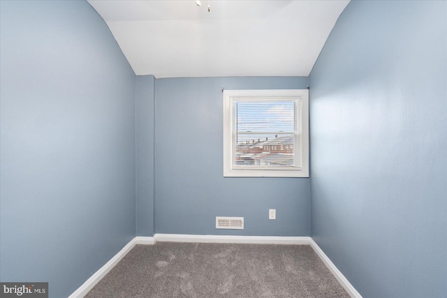 carpeted spare room featuring vaulted ceiling