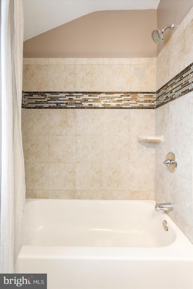 bathroom featuring shower / bathtub combination with curtain and lofted ceiling