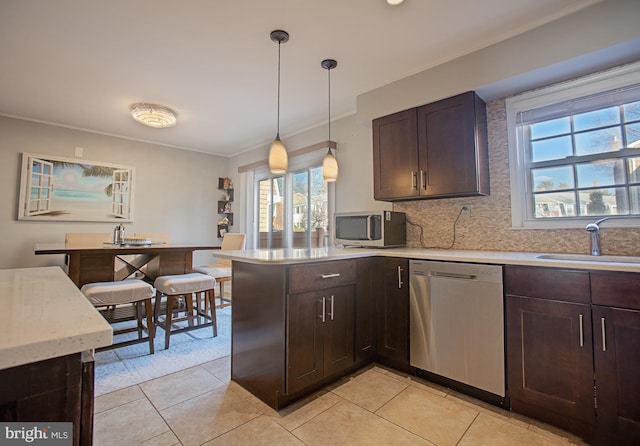 kitchen with hanging light fixtures, appliances with stainless steel finishes, light countertops, and a sink