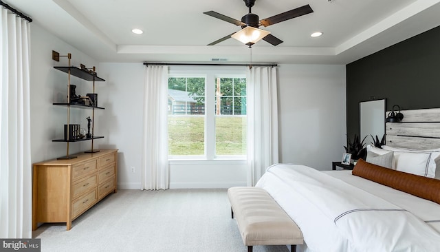 bedroom featuring a raised ceiling, ceiling fan, and light carpet