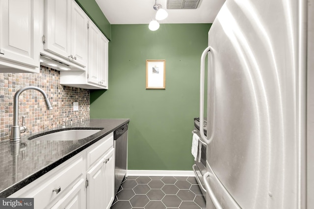 kitchen with white cabinetry, sink, dark tile patterned floors, backsplash, and appliances with stainless steel finishes