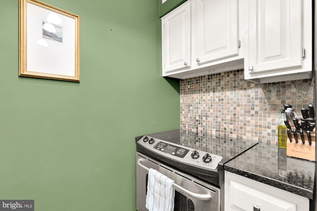 kitchen featuring tasteful backsplash, white cabinetry, stainless steel range with electric stovetop, and dark stone countertops