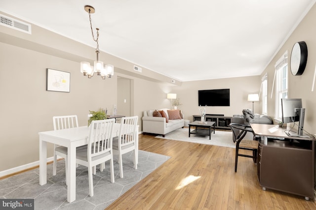 dining room with light wood-type flooring, an inviting chandelier, and crown molding