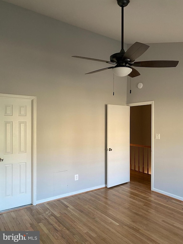 empty room featuring hardwood / wood-style floors, ceiling fan, and a high ceiling