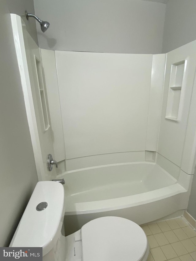 bathroom with tile patterned flooring, washtub / shower combination, and toilet