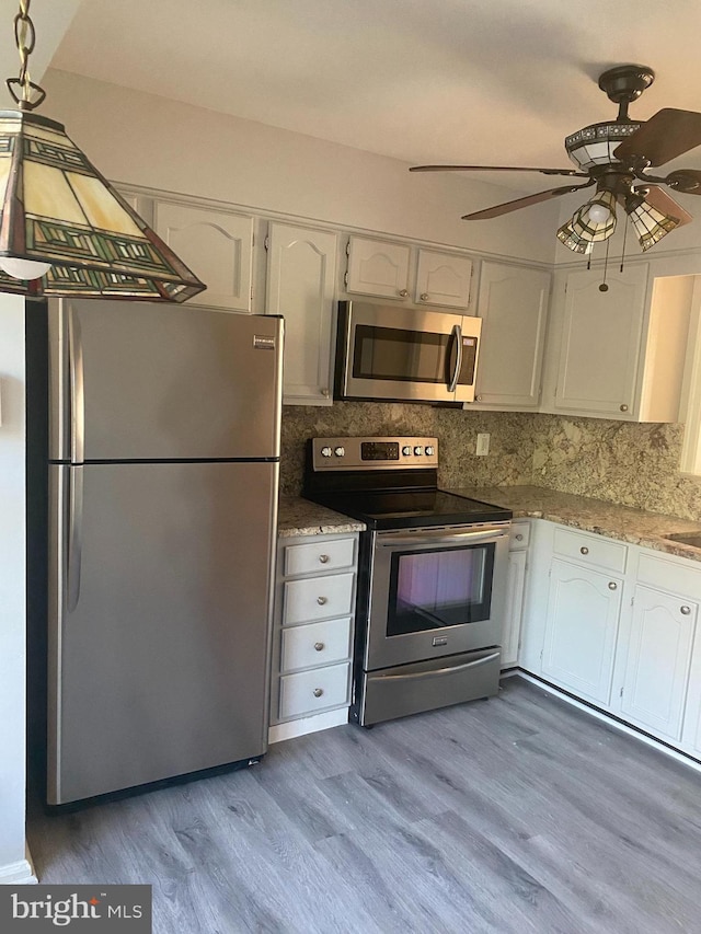 kitchen featuring appliances with stainless steel finishes, tasteful backsplash, ceiling fan, light hardwood / wood-style flooring, and white cabinetry