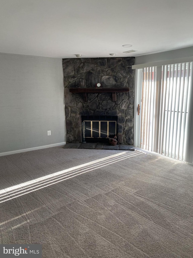 unfurnished living room with a stone fireplace and carpet floors