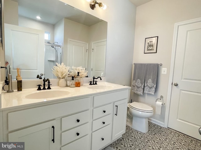 bathroom with tile patterned flooring, vanity, a shower with shower door, and toilet