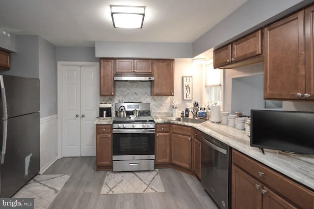 kitchen with decorative backsplash, stainless steel appliances, light hardwood / wood-style floors, and sink