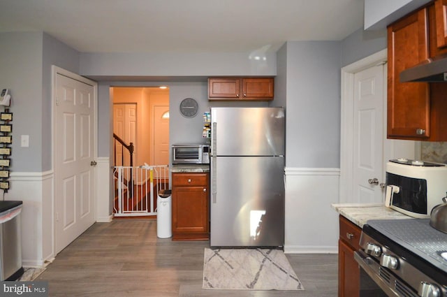 kitchen with light stone counters, stainless steel appliances, and dark wood-type flooring