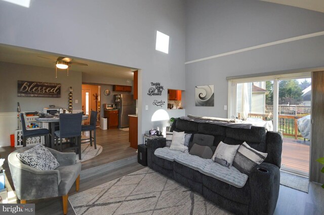 living room with ceiling fan, light hardwood / wood-style flooring, and high vaulted ceiling