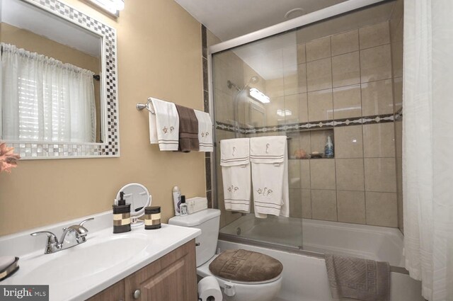 full bathroom featuring shower / bath combination with glass door, vanity, and toilet