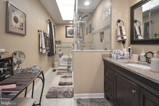 bathroom featuring a shower, vanity, a skylight, and tile patterned floors