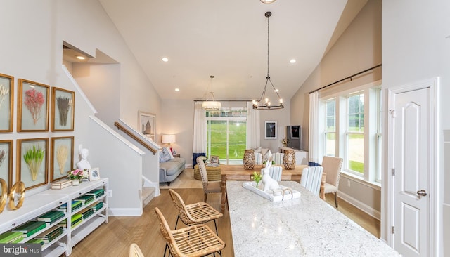 living room with high vaulted ceiling, a chandelier, and light hardwood / wood-style floors