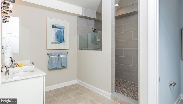 bathroom with tile patterned flooring, vanity, and tiled shower