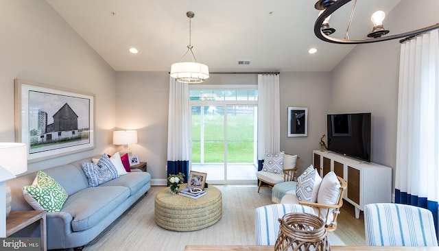 living room featuring hardwood / wood-style floors, vaulted ceiling, and a chandelier