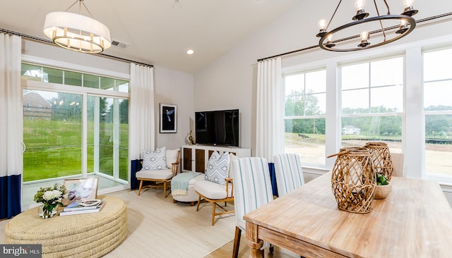 dining area with hardwood / wood-style flooring, a healthy amount of sunlight, vaulted ceiling, and a notable chandelier