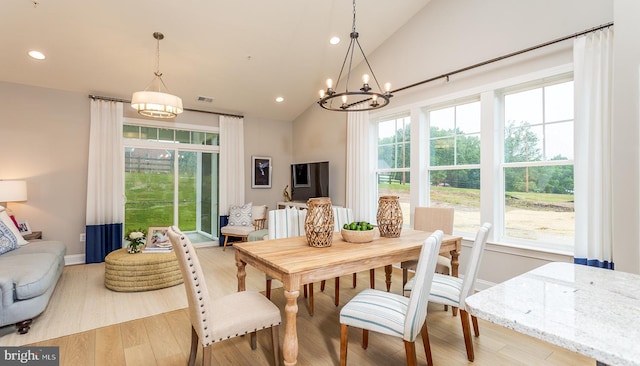 dining room with a chandelier, high vaulted ceiling, and light hardwood / wood-style flooring