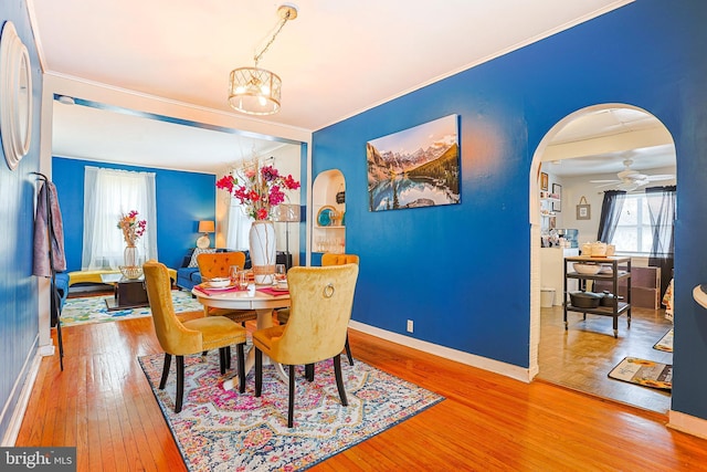 dining area featuring ceiling fan with notable chandelier, wood-type flooring, and crown molding