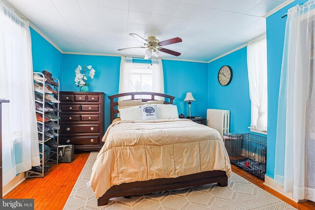 bedroom with wood-type flooring, ceiling fan, ornamental molding, and radiator