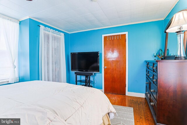 bedroom featuring dark hardwood / wood-style flooring, ornamental molding, and a closet