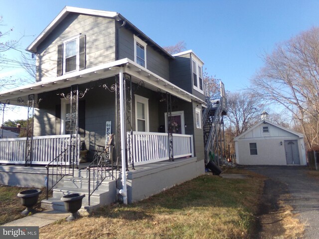 view of front of property featuring a porch, a garage, and an outdoor structure