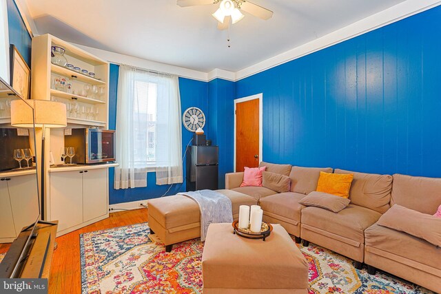 living room featuring bar area, ceiling fan, and wood-type flooring